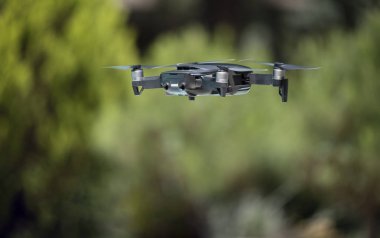 yeşil bir arka plan üzerinde uçan koyu gri drone