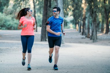 bir parkta koşan çift birbirlerine bakıyor ve müzik dinlerken gülümsüyor