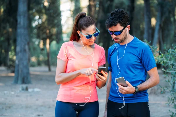 Caucasian couple watching mobile application and exercising in a park. Healthy living concept
