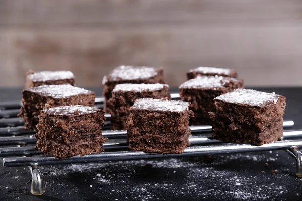 棕色背景的钢网上的方块巧克力和糖玻璃蛋糕 — 图库照片