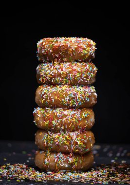 Çilek şurubuyla donut dağı ve siyah arka planda renkli bir kaplama.