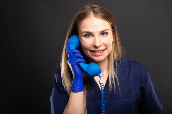 Médico Femenino Vistiendo Bata Que Habla Receptor Teléfono Azul Sonriendo —  Fotos de Stock