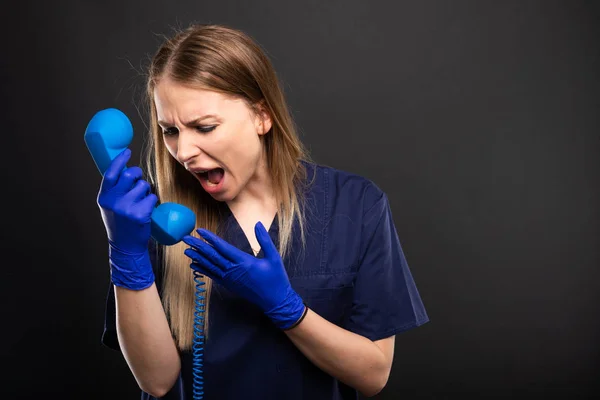 Médica Mulher Vestindo Esfrega Gritando Com Receptor Telefone Fundo Preto — Fotografia de Stock