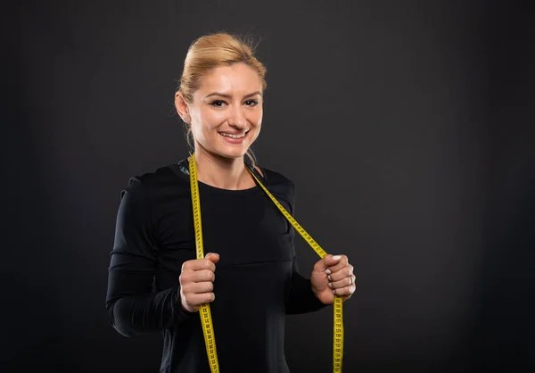Pretty Gym Female Trainer Holding Measuring Tape Smiling Black Background — Stock Photo, Image