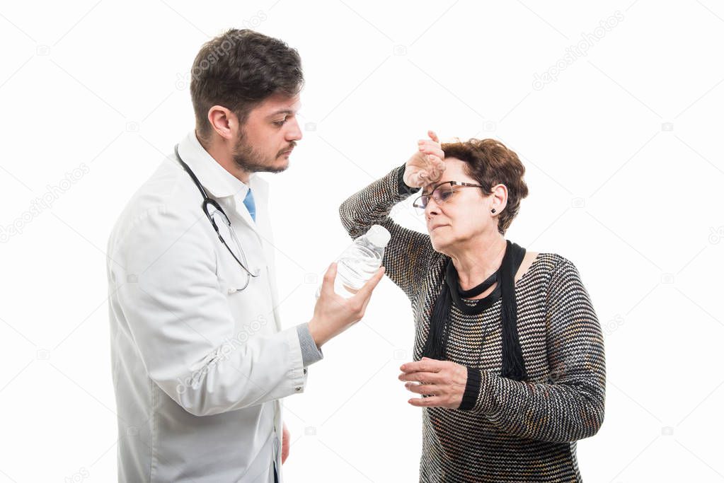 Male doctor offering water to thirsty female senior patient isolated on white background
