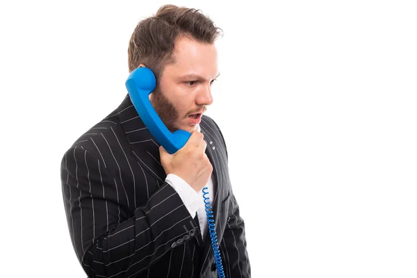 Copyspace 折込広告エリアで白い背景に分離された青い受話器で話しているビジネスの男のポートレート — ストック写真