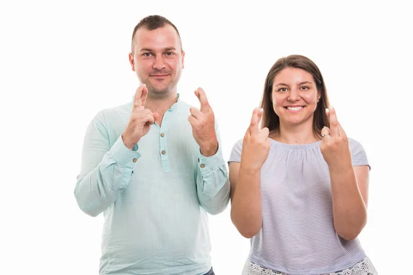 年轻幸福夫妇的肖像显示双交叉手指手势在白色背景下与 Copyspace 广告区隔离 — 图库照片