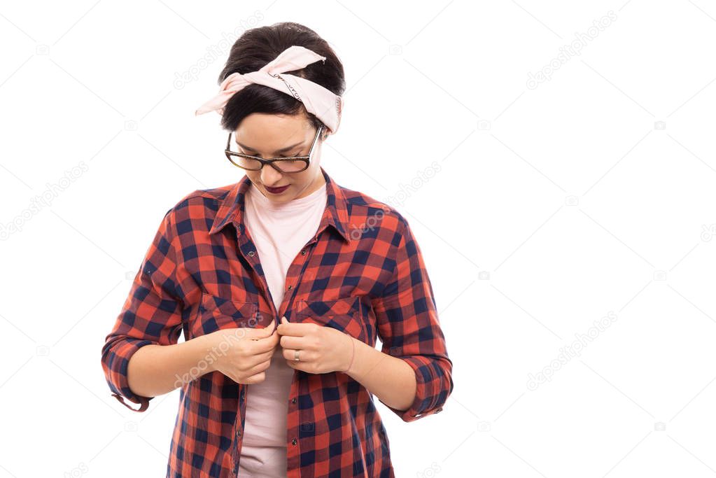 Portrait of young pretty pin-up girl wearing glasses buttoning shirt isolated on white background with copyspace advertising area