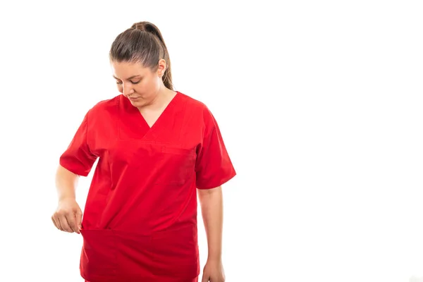 Copyspace 折込広告エリアで白い背景で隔離のポケットに赤のスクラブを着ている若い医療看護師の肖像 — ストック写真
