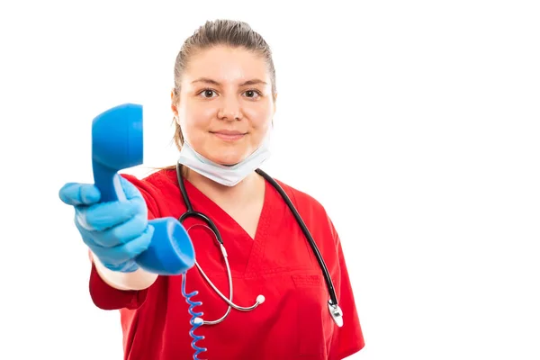 Copyspace 折込広告エリアで白い背景に分離された青い受信機を保持している赤のスクラブを着ている若い医療看護師の肖像 — ストック写真