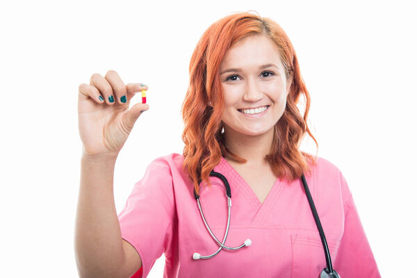 Портрет молодой женщины-врача со стетоскопом, держащей двойную цветную таблетку, изолированную на белом фоне с зоной рекламы в копировальном пространстве
