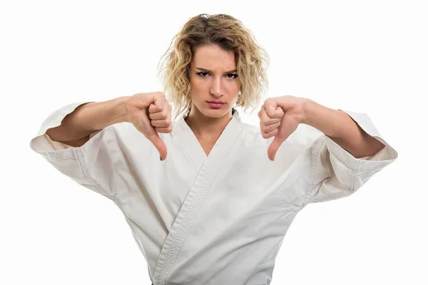 Portrait of young female wearing martial arts uniform showing double dislike gesture isolated on white background