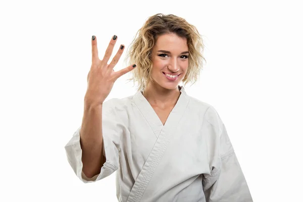 Portrait of female wearing martial arts uniform showing number four isolated on white background with copy space advertising area