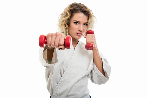 Portrait of female wearing martial arts costume training with dumbbells isolated on white background with copy space advertising area