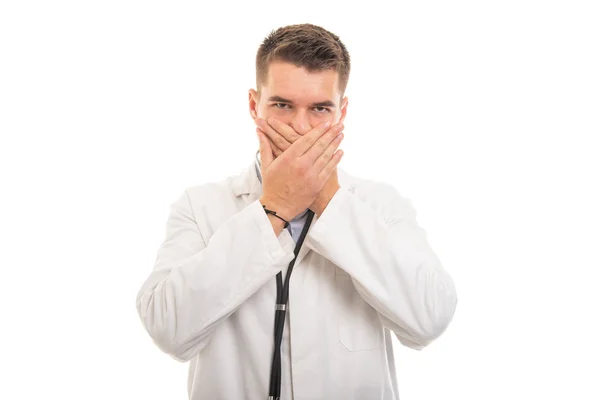Retrato de un joven médico guapo cubriendo la boca como un cono mudo —  Fotos de Stock