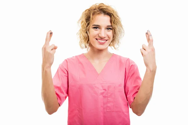 Portret pielęgniarki ubrany różowy peeling trzymając podwójne palce CROS — Zdjęcie stockowe
