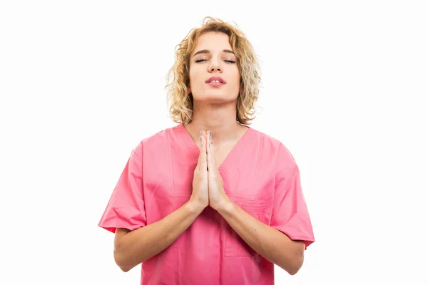 Porträt einer Krankenschwester, die ein rosafarbenes Peeling trägt und Gebetsgeste macht — Stockfoto