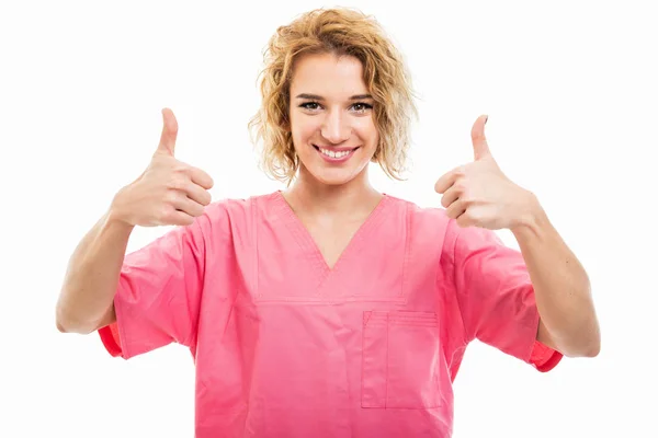 Portrait of young nurse wearing pink scrub showing double like g — Stock Photo, Image