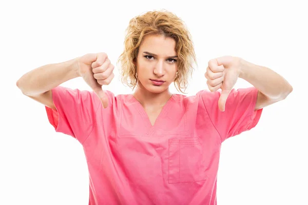 Retrato de jovem enfermeira vestindo esfoliação rosa mostrando dislik duplo — Fotografia de Stock