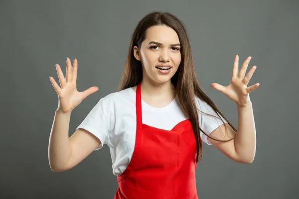 Portrait of young female supermarket employee yelling looking mad on gray background