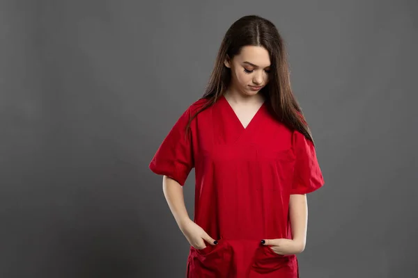 Schöne Junge Krankenschwester Prüft Ihre Vordertaschen Auf Grauem Hintergrund Und — Stockfoto