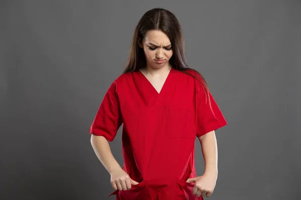 Enfermera Atractiva Triste Mira Sus Bolsillos Vacíos Usando Ropa Roja — Foto de Stock