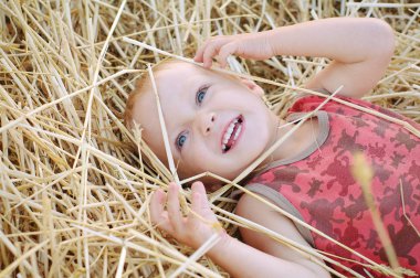 Buğday tarlası samanlıkta oturan bir yaz şapkalı küçük çocuk portresi. Güzel gün batımı