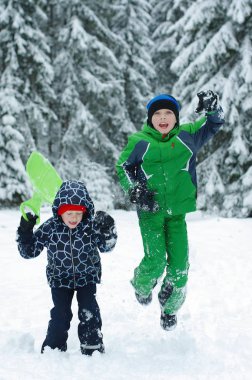 Mutlu çocuklar üzerinde bir kış oynama doğada yürüyüş. Atlama ve having fun kış Park çocuk