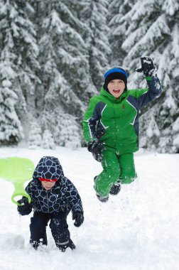 Mutlu çocuklar üzerinde bir kış oynama doğada yürüyüş. Atlama ve having fun kış Park çocuk