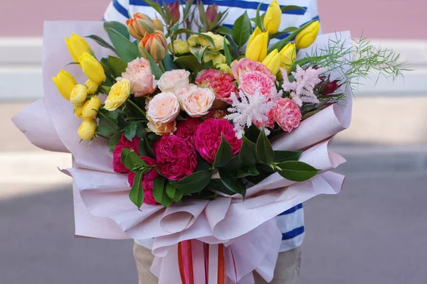 Um menino sorridente de pé com um buquê de flores. Lindas flores para mãe — Fotografia de Stock