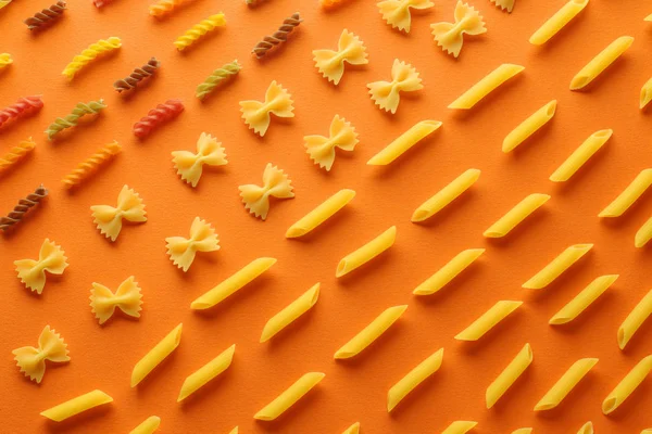 Verschiedene Arten Von Pasta Auf Orangefarbenem Hintergrund Organisiert Flache Lagekonzeption — Stockfoto