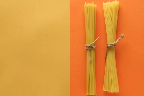 Vollkornspaghetti auf leuchtend gelbem und orangefarbenem Hintergrund. Ansicht von oben. Text platzieren — Stockfoto