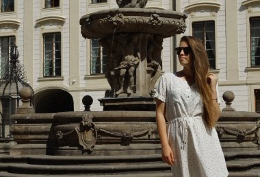 Prag 'daki Prag Kalesi' nde güneşli bir günde fıskiyenin yanında poz veren genç kız öğrenci.