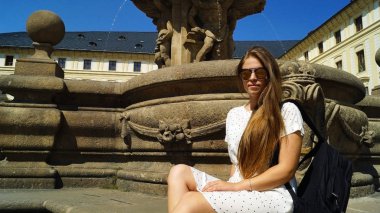 Prag 'daki Prag Kalesi' nde güneşli bir günde fıskiyenin yanında poz veren genç kız öğrenci.