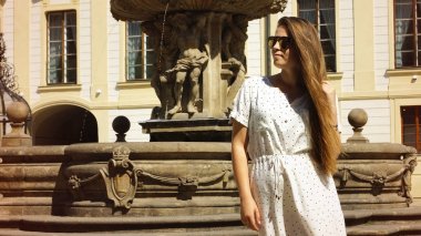 Prag 'daki Prag Kalesi' nde güneşli bir günde fıskiyenin yanında poz veren genç kız öğrenci.