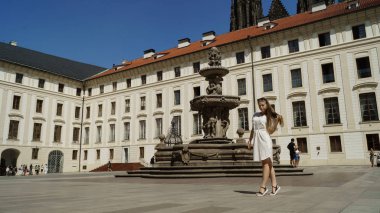 Prag 'daki Prag Kalesi' nde güneşli bir günde fıskiyenin yanında poz veren genç kız öğrenci.