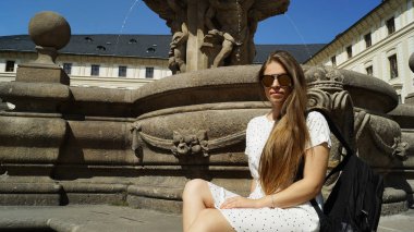 Prag 'daki Prag Kalesi' nde güneşli bir günde fıskiyenin yanında poz veren genç kız öğrenci.