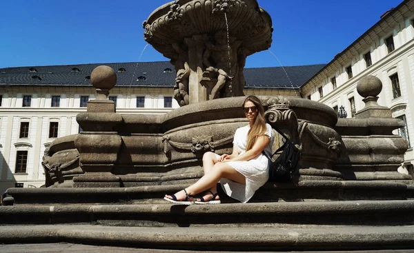 Junge Studentin posiert am Brunnen an einem sonnigen Tag auf der Prager Burg in Prag — Stockfoto