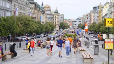 Turistler Prag'ın merkezindeki Wenceslas Meydanı'nda güneşli bir günde yürüyorlar.