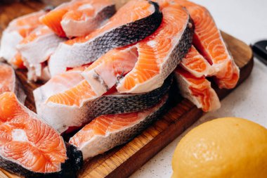 Dilimlenmiş kırmızı balık parçaları mutfaktaki tahta tahtada yatıyor.