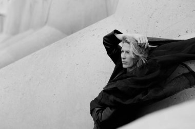 Güzel kadın portre, uçan siyah eşarp ve sarı uzun saçlı, beton blok arka planda liman