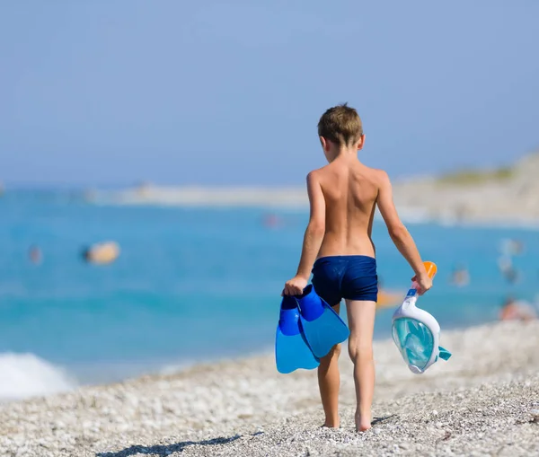 小男孩走在海滩游泳与浮潜面具和蓝色鳍片 — 图库照片