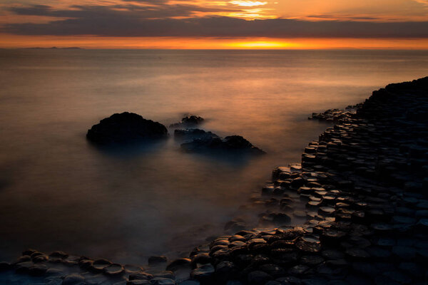 Sunset and unique shaped coastal rocks at Giants Causeway, North Ireland