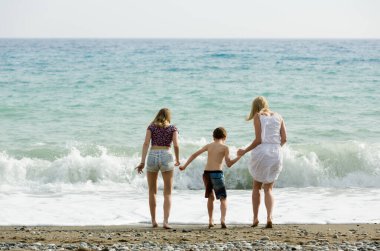 Aile kumsalda dalgalarla oynar.