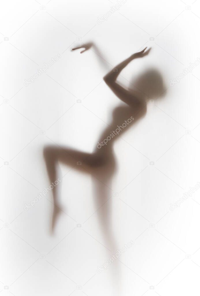 Pretty female human dancing body shape silhouette behind a white glass like curtain.