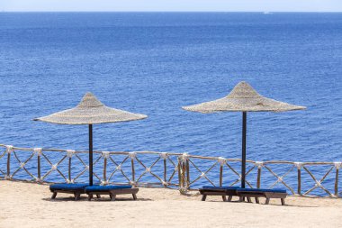 İki yanındaki Kızıldeniz Resort, Sharm El Sheikh, Mısır ahşap şezlong ile hasır şemsiyeler plaj