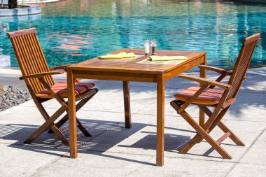 Ahşap masa ve sandalyeler beach Restaurant'ta Tayland yüzme havuzu yanında. Yakın çekim