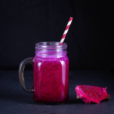 Dragon meyve muz, mango ve papaya cam kupa siyah arka plan, üzerine gelen taze smoothies kapatın. Sağlıklı beslenme kavramı