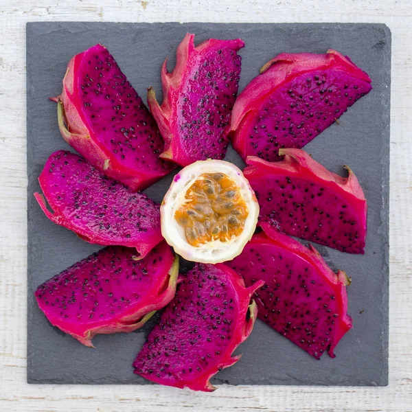 Exotic pink dragon fruit cut and passionfruit on background close up. Sweet tropical fruit, juicy pitaya and passion fruit cut