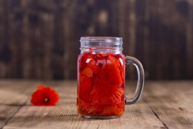 Kırmızı haşhaş çiçek çay içecek cam kupa ahşap zemin üzerine kapatın. Sağlıklı beslenme kavramı